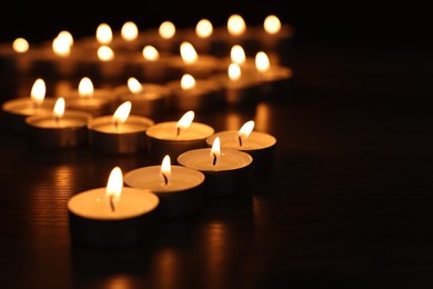 Photo of Burning candles on dark surface, closeup. Space for text