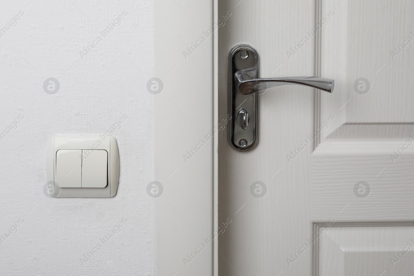 Photo of Modern light switch on white wall near door