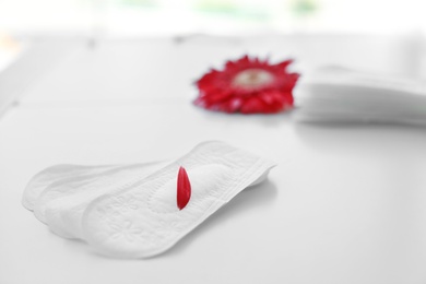 Menstrual pads with red flower petal on table. Gynecological care