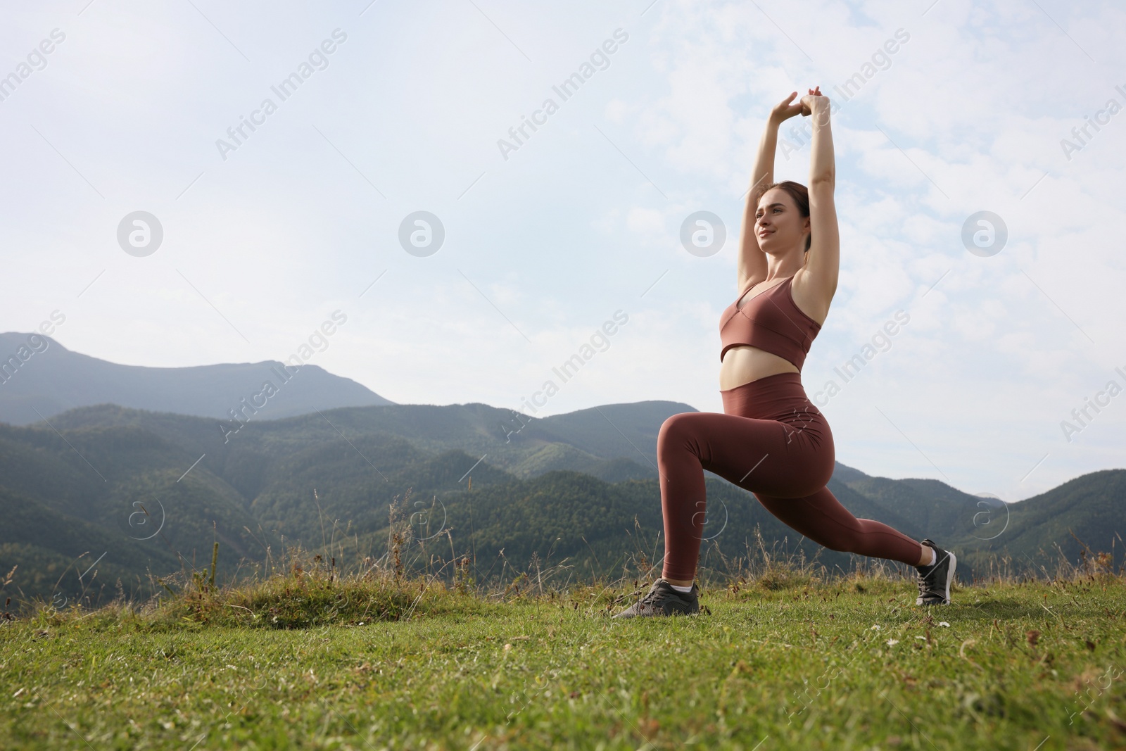 Photo of Young woman doing morning exercise in mountains, space for text