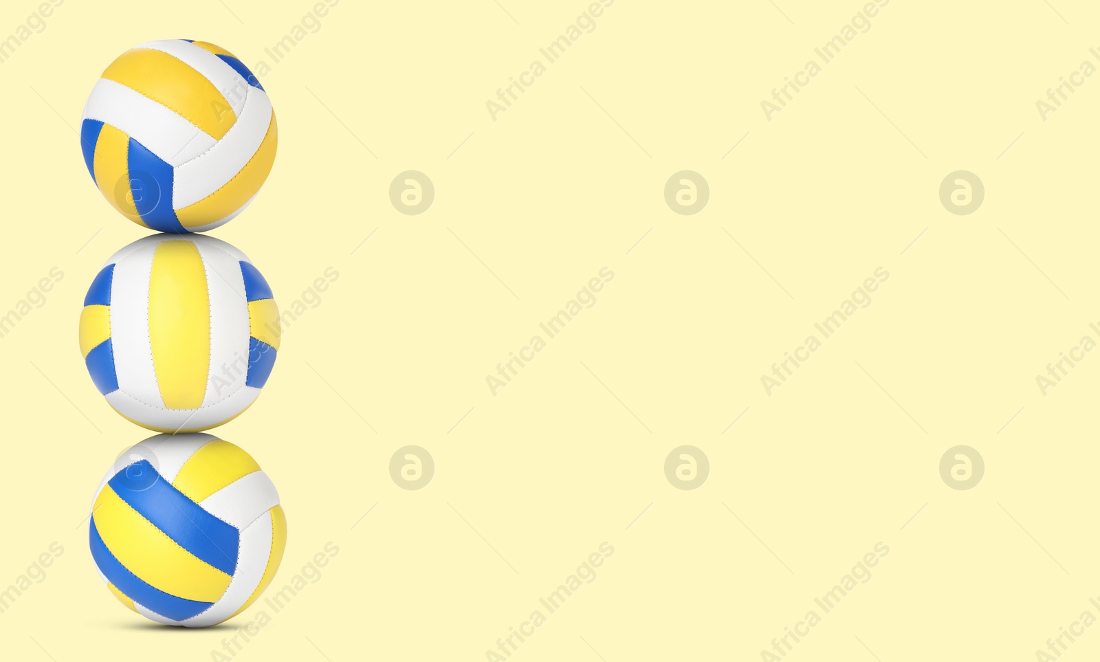 Image of Stack of volleyball balls on pale light yellow background. Space for text