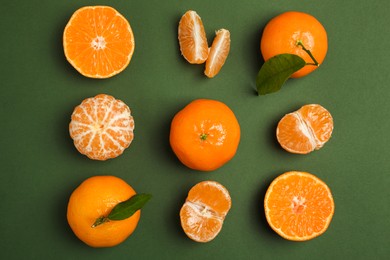 Delicious tangerines with leaves on green background, flat lay