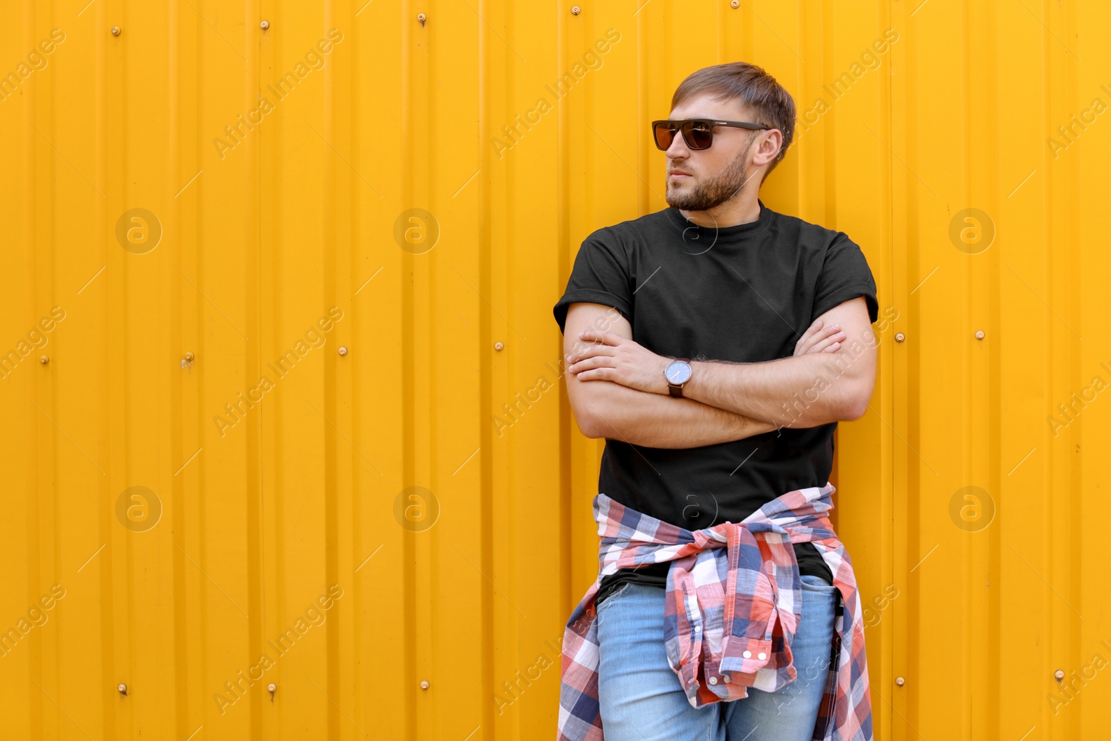 Photo of Young man wearing black t-shirt near color wall on street