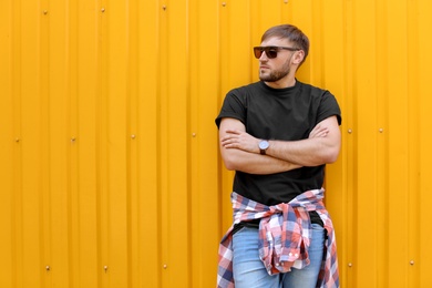 Young man wearing black t-shirt near color wall on street