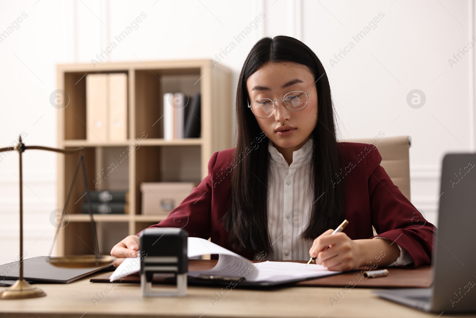 Photo of Notary signing document at table in office