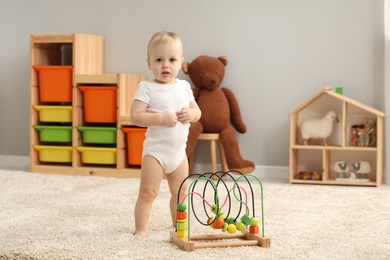 Photo of Children toys. Cute little boy and bead maze on rug at home