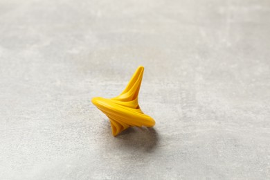 Photo of Yellow spinning top on grey textured background, closeup