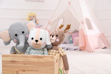 Photo of Wooden crate with cute toys in stylish playroom, space for text. Interior design