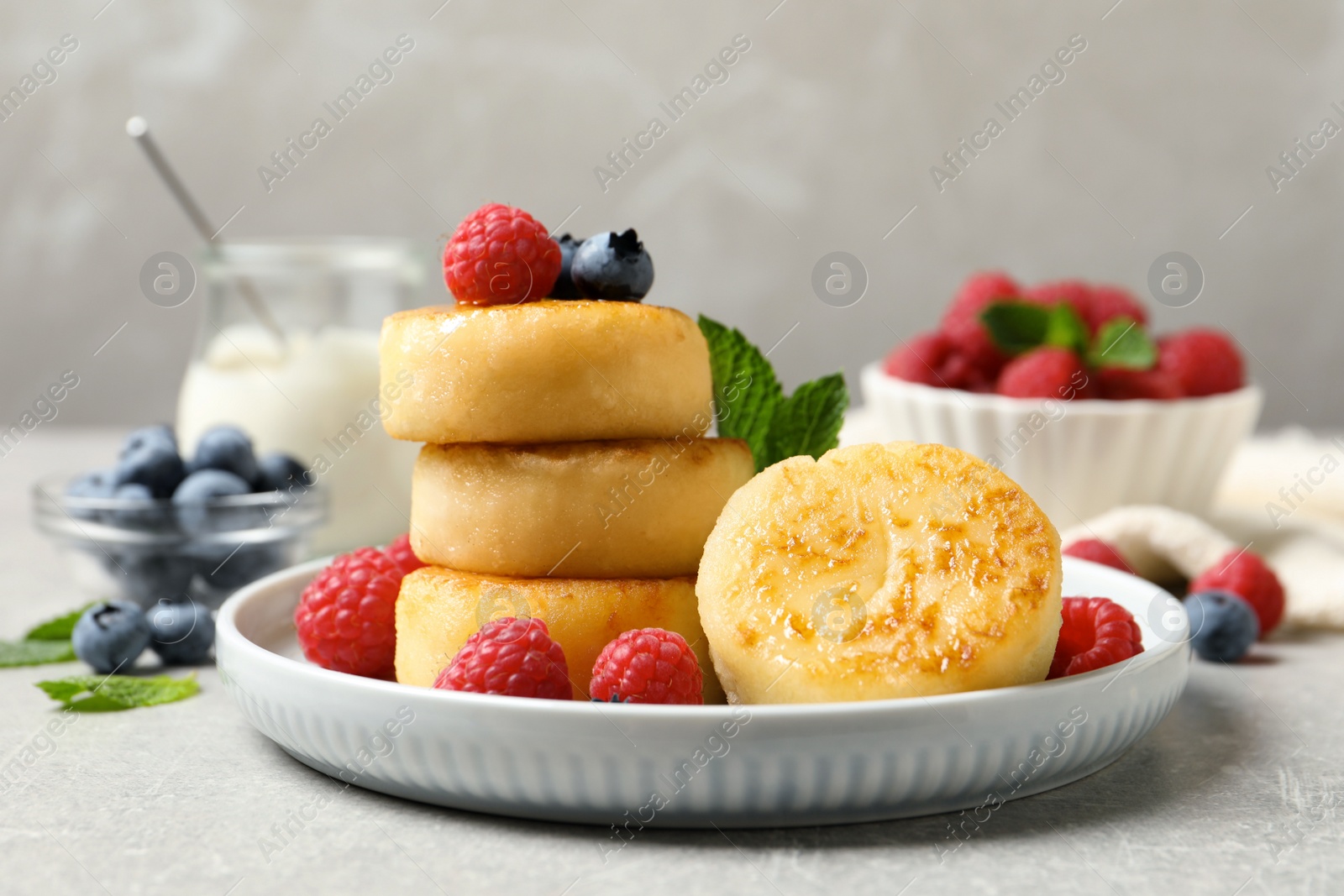 Photo of Delicious cottage cheese pancakes with berries on light table