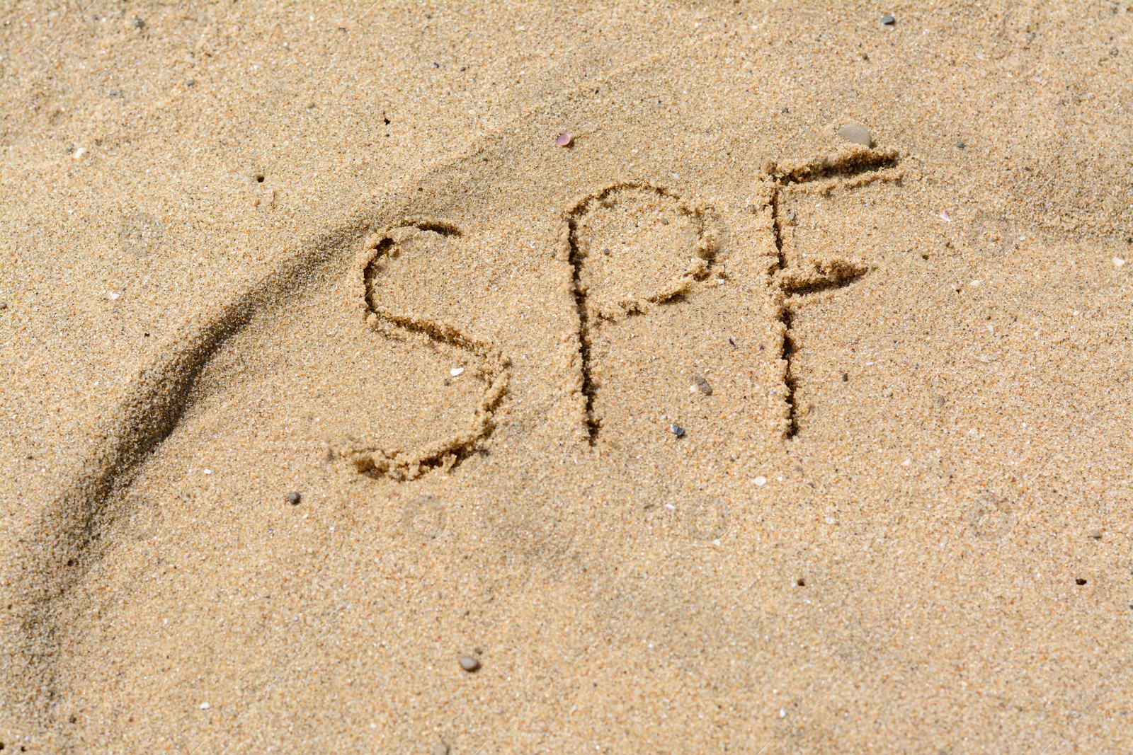 Photo of Abbreviation SPF written on sand at beach, above view