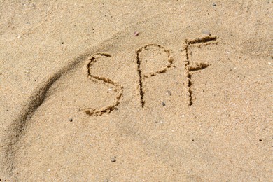 Photo of Abbreviation SPF written on sand at beach, above view
