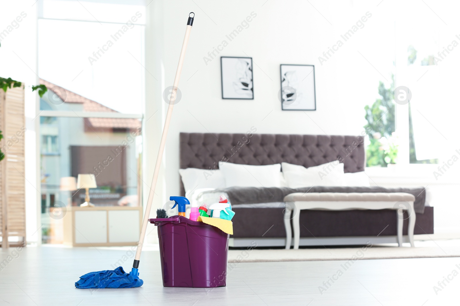 Photo of Bucket with cleaning supplies and mop on floor indoors