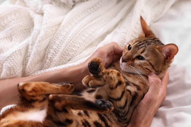 Photo of Woman with cute Bengal cat on bed at home, closeup. Adorable pet