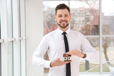Photo of Real estate agent holding house model, indoors