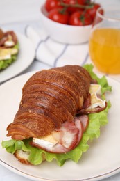 Photo of Tasty croissant with brie cheese, ham and bacon on table