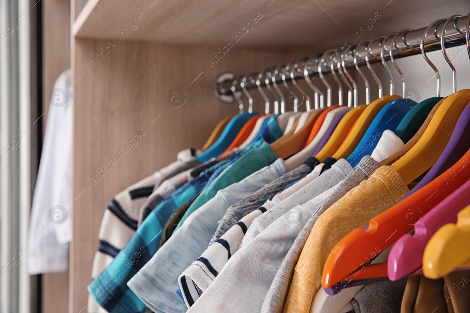 Photo of Stylish boy's clothes hanging in wardrobe, closeup