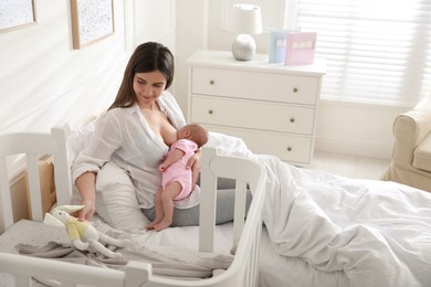 Photo of Happy young mother breastfeeding her newborn baby at home