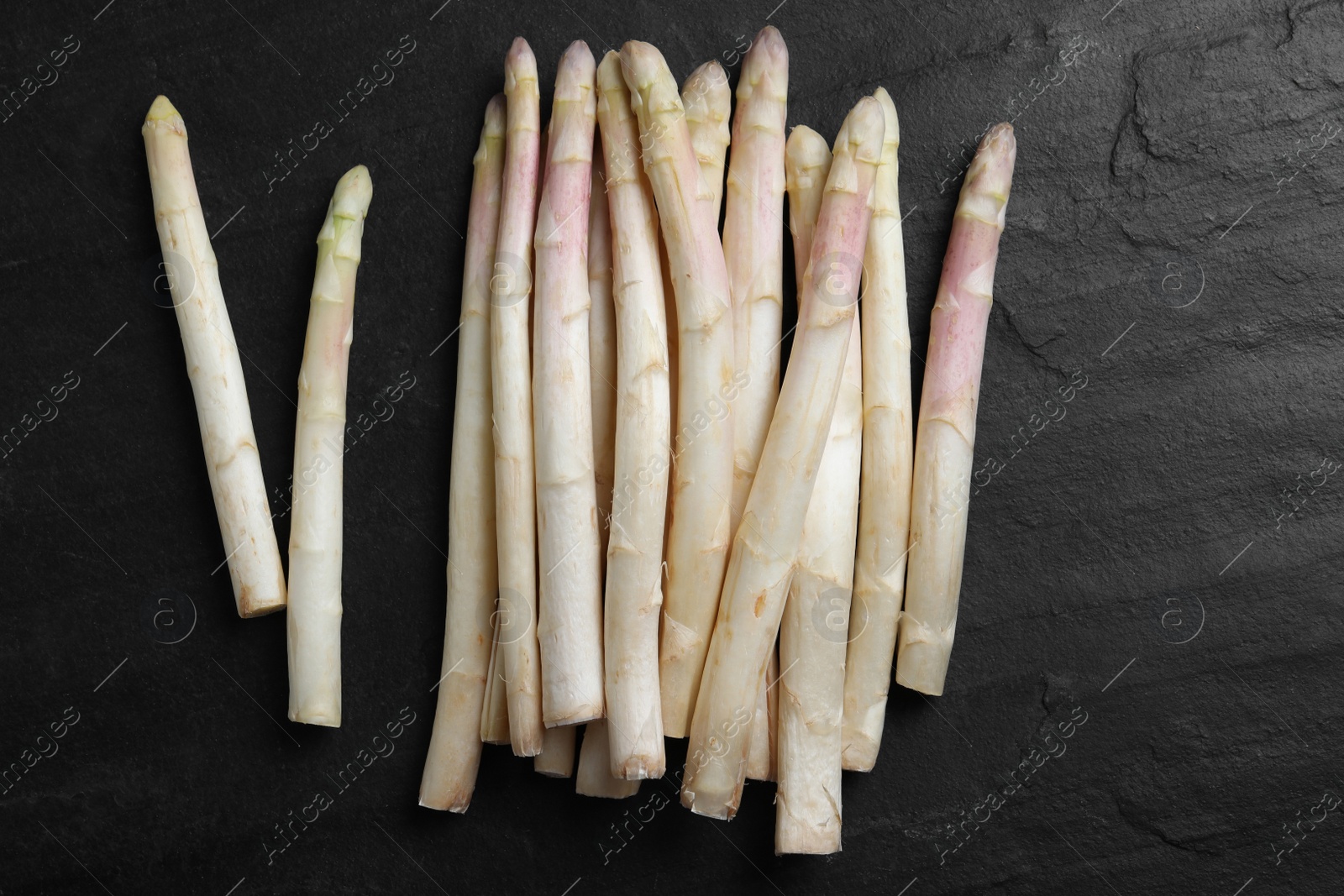 Photo of Fresh white asparagus on black table, flat lay