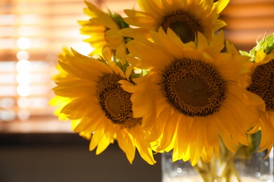 Photo of Bouquet of beautiful sunflowers in vase indoors, closeup
