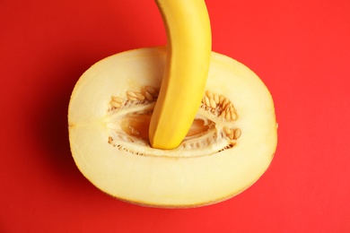 Flat lay composition with fresh banana and melon on red background. Sex concept