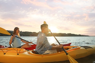 Photo of Couple kayaking on river at sunset. Summer activity