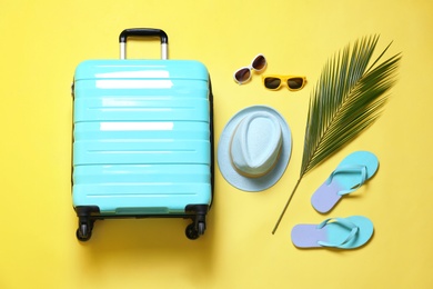 Flat lay composition with stylish suitcase on yellow background