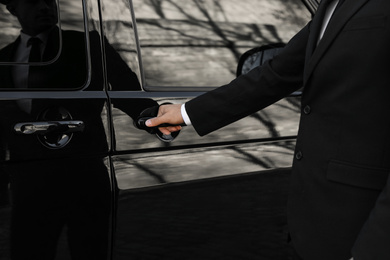 Photo of Driver opening door of luxury car, closeup. Chauffeur service