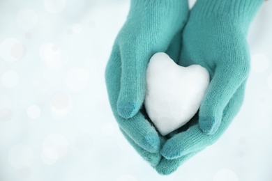 Photo of Woman holding heart shaped snowball in hands, closeup