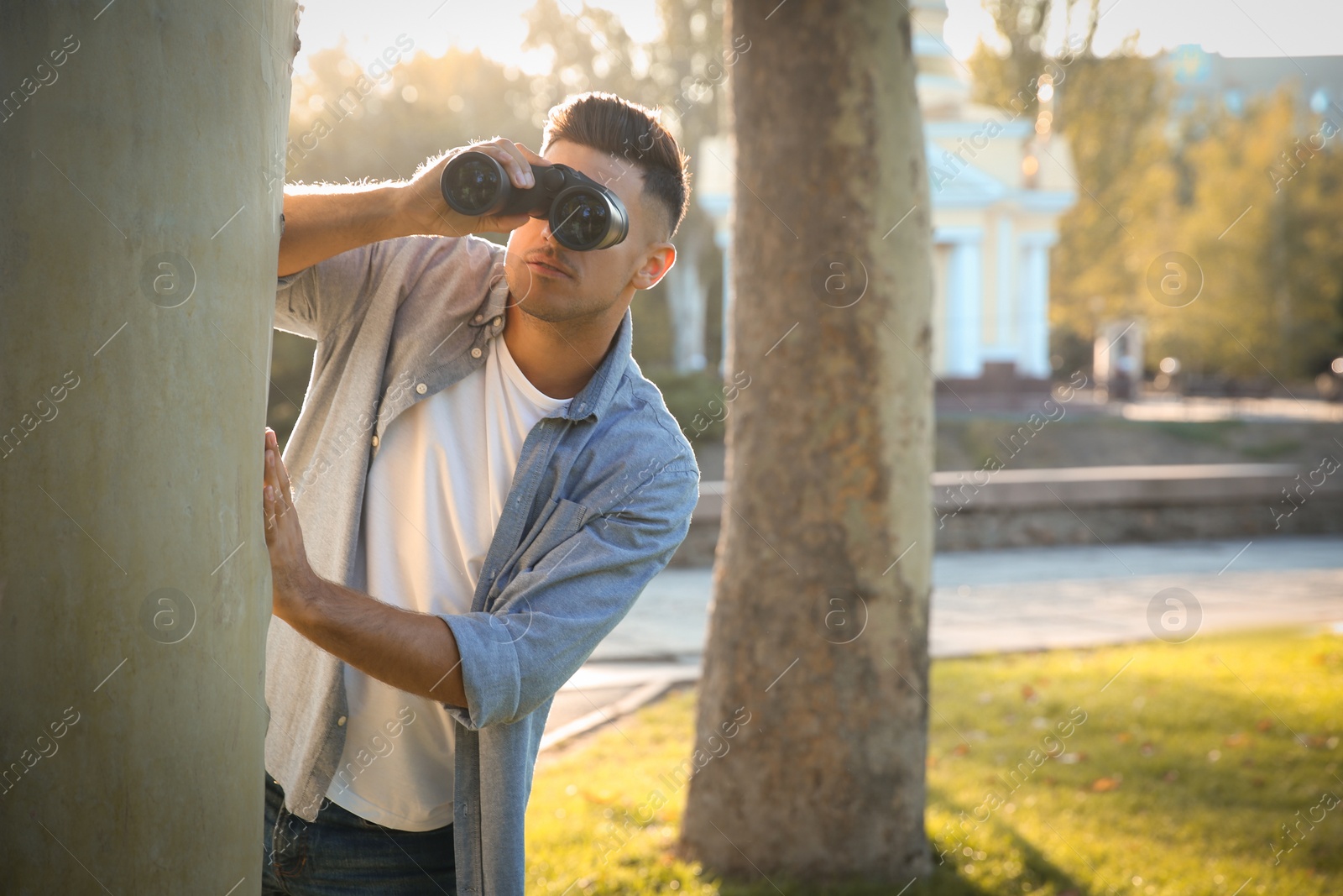 Photo of Jealous man with binoculars spying on ex girlfriend in park