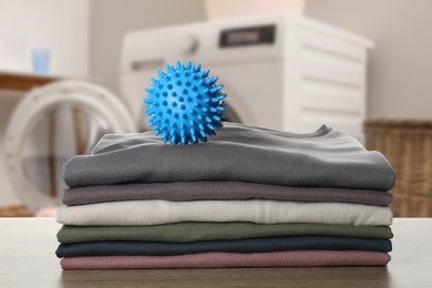 Image of Dryer ball and stacked clean clothes on wooden table in laundry room