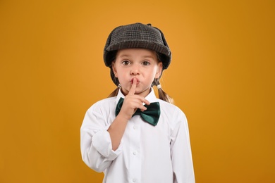Photo of Cute little detective in hat on yellow background