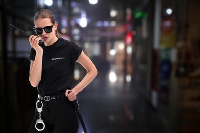 Female security guard using portable radio transmitter in shopping mall at night