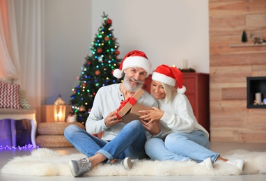 Happy couple opening Christmas gift at home