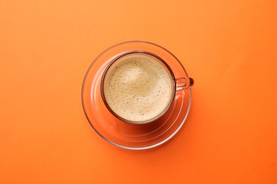 Fresh coffee in cup on orange background, top view
