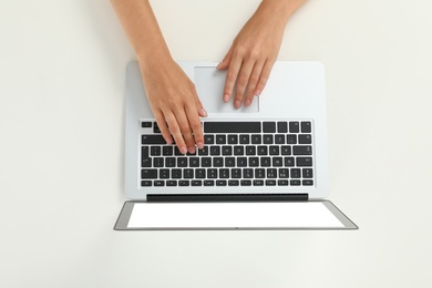 Woman using modern laptop on light background, top view