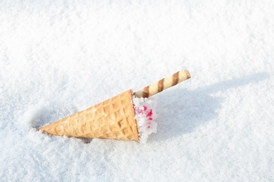 Photo of Waffle cone with ice cream on snow, space for text
