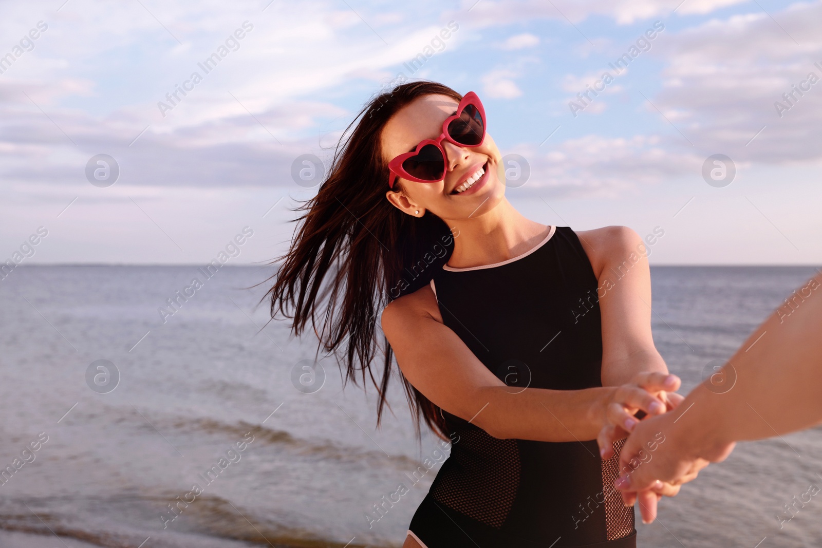 Photo of Young woman holding hands with girlfriend on beach