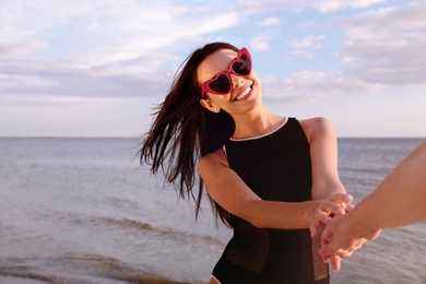 Photo of Young woman holding hands with girlfriend on beach