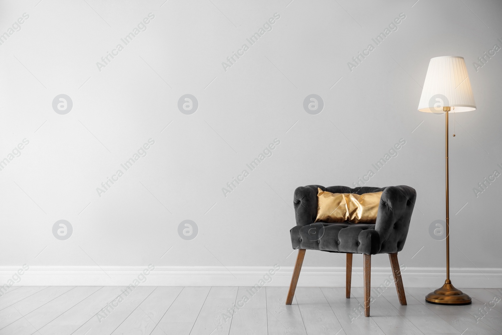 Photo of Stylish room interior with comfortable armchair, floor lamp near light wall, space for text