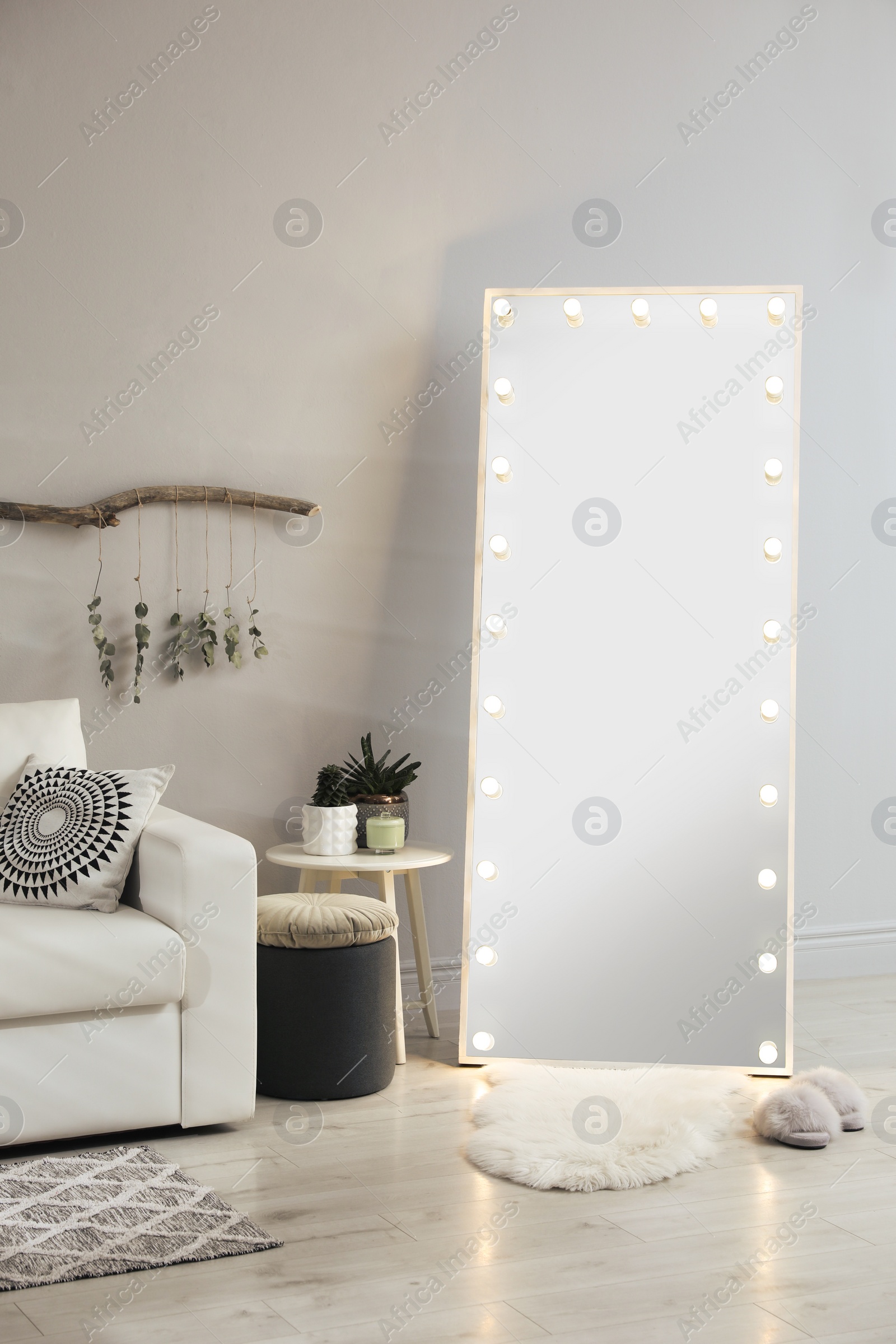 Photo of Stylish mirror with light bulbs and comfortable sofa in living room. Interior design