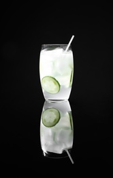 Photo of Glass of delicious cucumber martini with ice on dark background