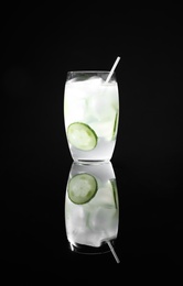 Glass of delicious cucumber martini with ice on dark background