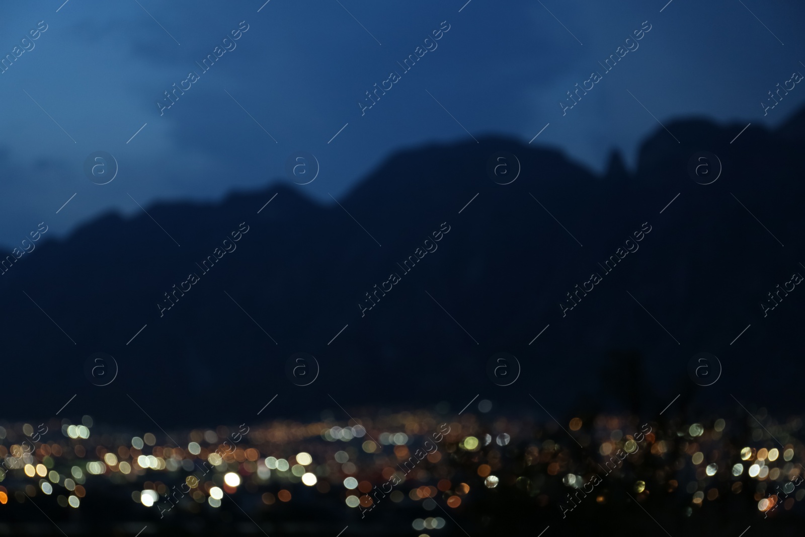 Photo of Blurred view of beautiful city near mountains at night. Bokeh effect