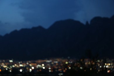 Photo of Blurred view of beautiful city near mountains at night. Bokeh effect