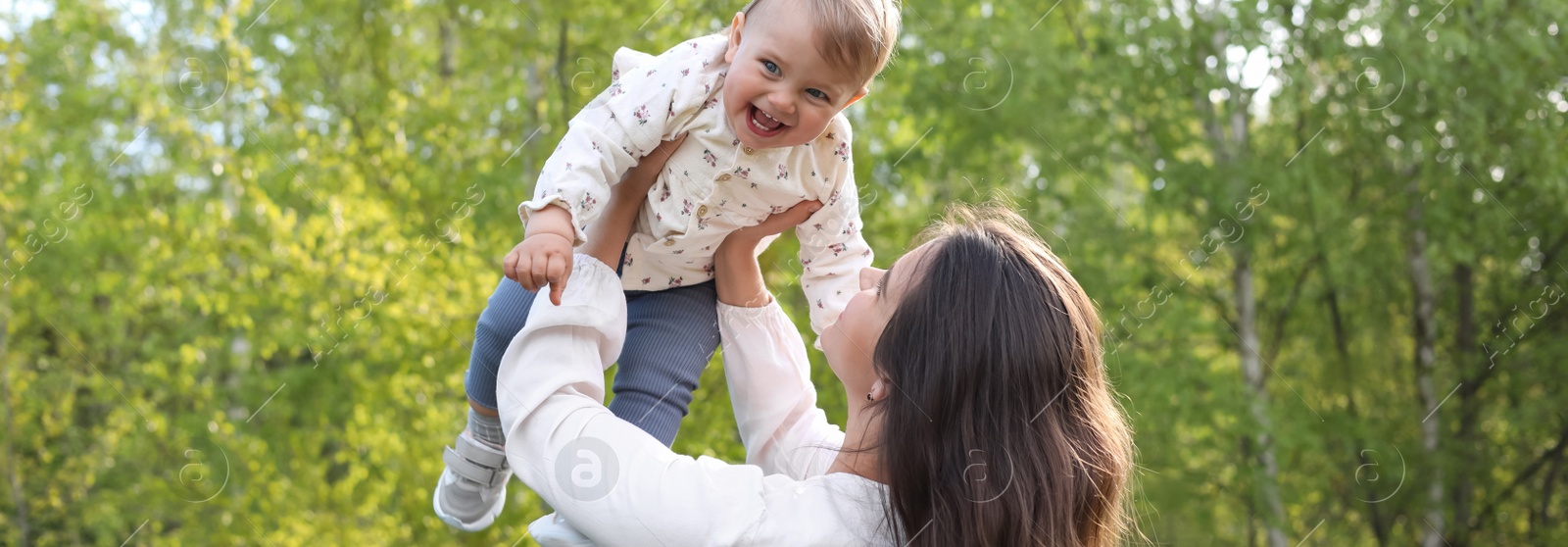 Image of Happy mother playing with her cute baby in park on sunny day. Banner design