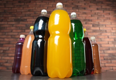 Photo of Bottles of soft drinks on table against brick wall, low angle view