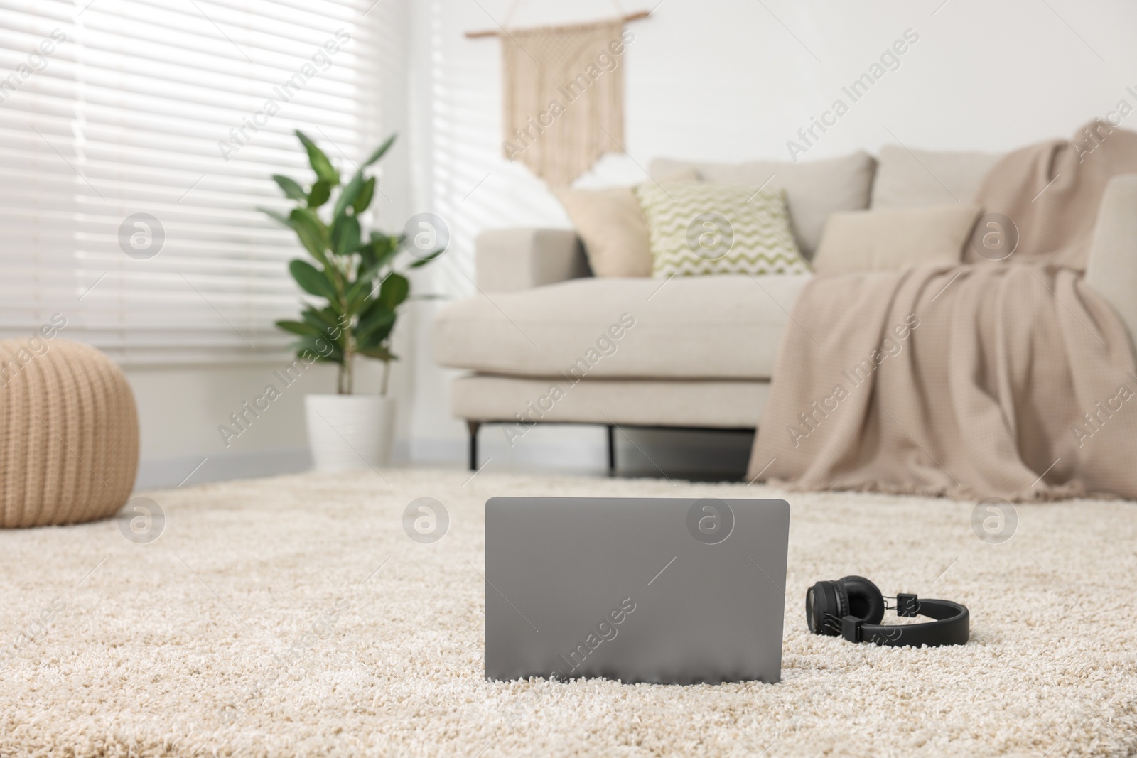 Photo of Modern laptop and headphones on carpet in living room