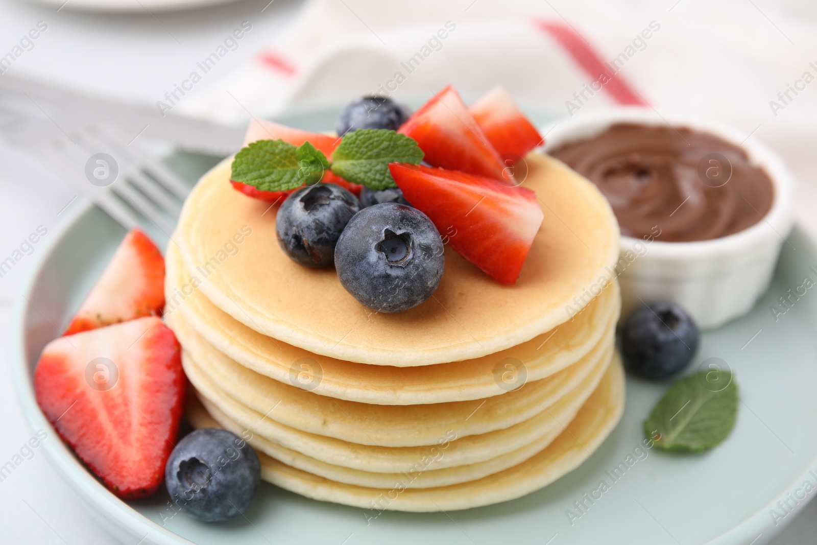 Photo of Delicious pancakes with strawberries, blueberries and mint on table, closeup