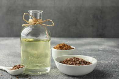Caraway (Persian cumin) seeds, powder and essential oil on gray textured table