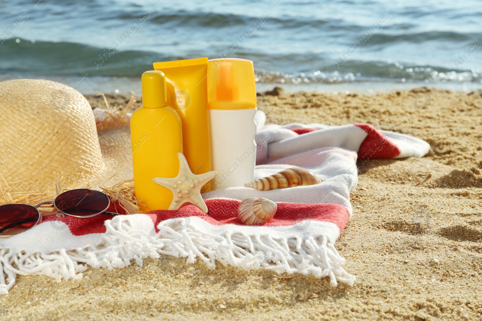 Photo of Sun protection products and beach accessories on blanket near sea, space for text